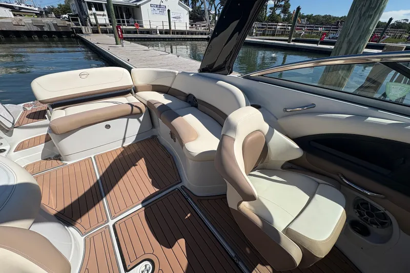 Slide: The Image of 2017 Crownline 275 SS boat interior with beige seating and wood flooring at a dock. - 21