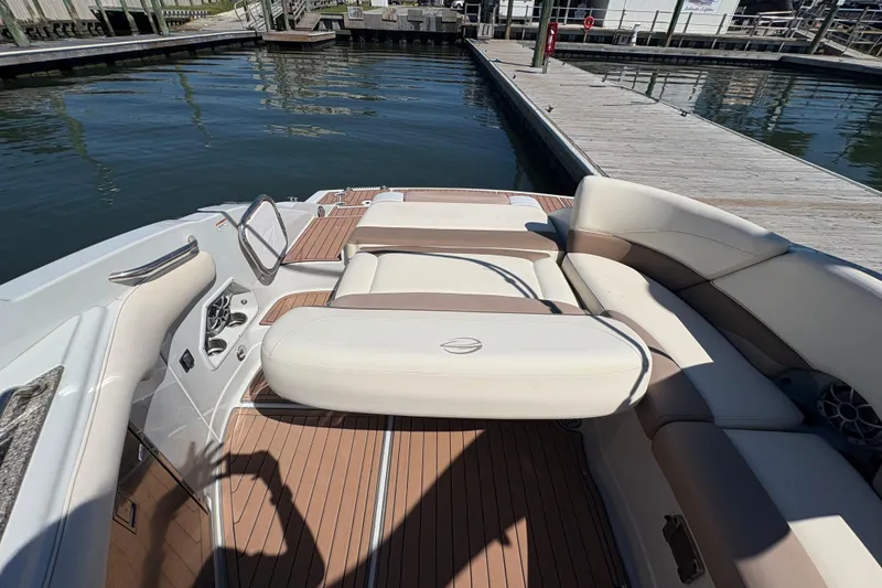 Slide: The Image of 2017 Crownline 275 SS boat interior with beige seating and wooden deck at a marina. - 27