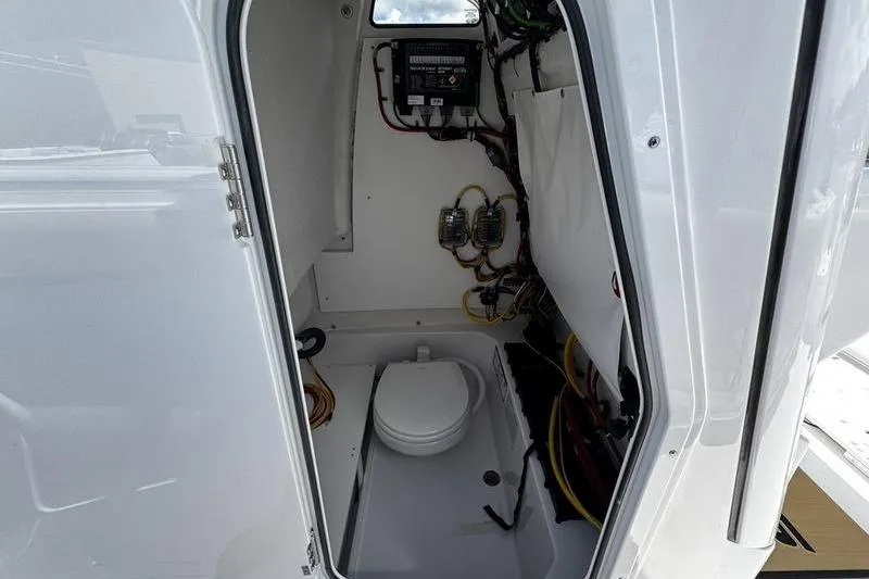 Slide: The Image of 2026 Sportsman Open 232 Center Console boat interior with marine toilet and wiring. - 10