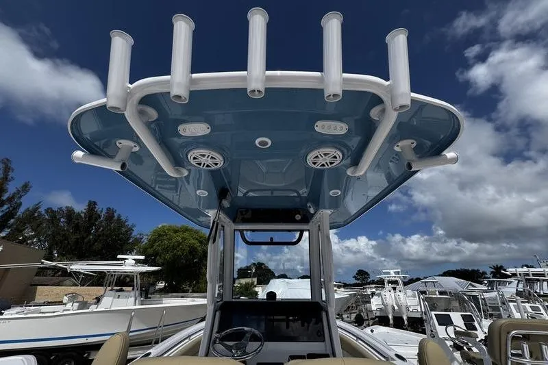 Slide: The Image of 2026 Sportsman Open 232 Center Console boat with rod holders and speakers under a blue sky. - 23