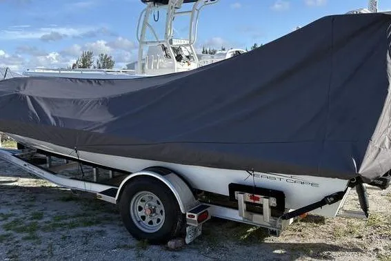 Slide: The Image of 2022 East Cape Vantage boat covered on trailer, parked outdoors under blue sky. - 12