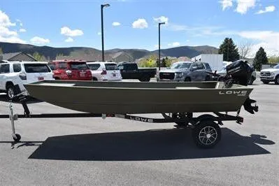 The Image of 2024 Lowe L1448 Jon boat on trailer in parking lot, surrounded by cars. - 0