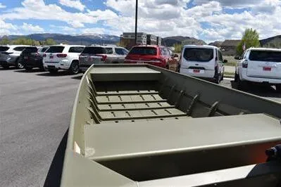 Slide: The Image of 2024 Lowe L1448 Jon boat in parking lot, surrounded by cars under a partly cloudy sky. - 8