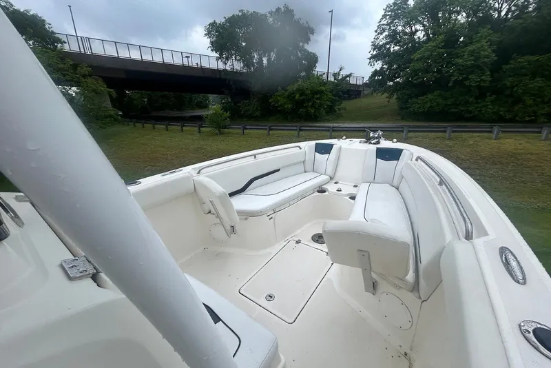 Slide: The Image of 2016 Wellcraft 242 Fisherman boat interior with white seating, near a bridge and greenery. - 4