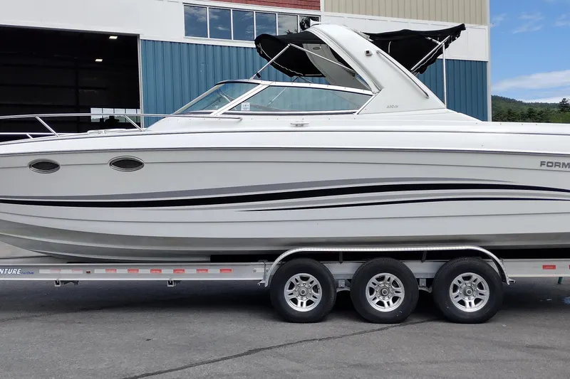 The Image of 2005 Formula 330 Sun Sport boat on trailer, white with black accents, parked outdoors. - 1