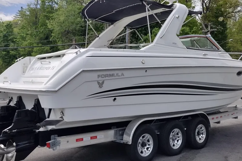 Slide: The Image of 2005 Formula 330 Sun Sport boat on trailer, featuring sleek white design and black canopy. - 6