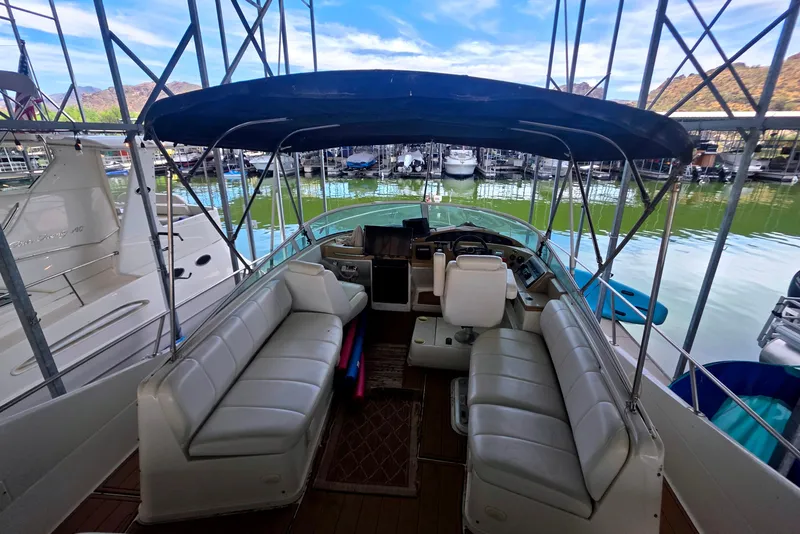 Slide: The Image of 2001 Carver 350 Mariner interior with seating, helm, and marina view under blue canopy. - 10