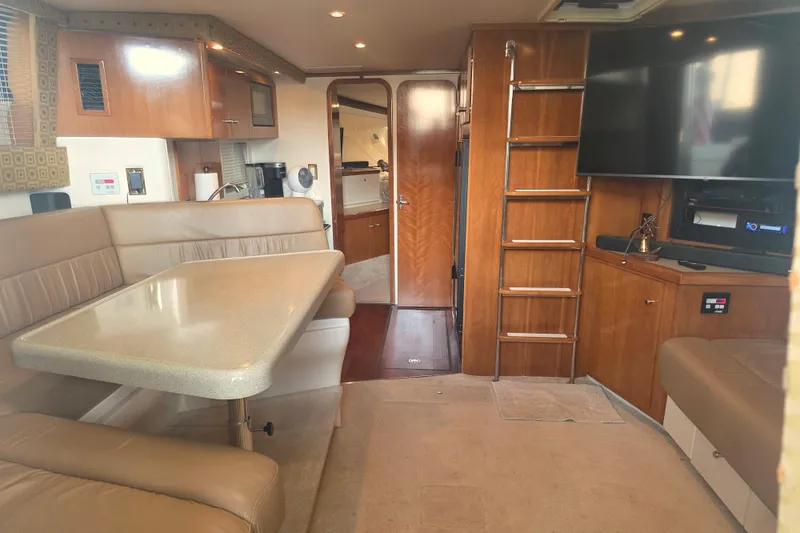 Slide: The Image of Interior of 2001 Carver 350 Mariner yacht with dining area, TV, and wooden cabinetry. - 24