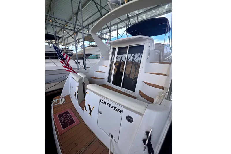 Slide: The Image of 2001 Carver 350 Mariner yacht docked, featuring American flag and spacious deck area. - 4