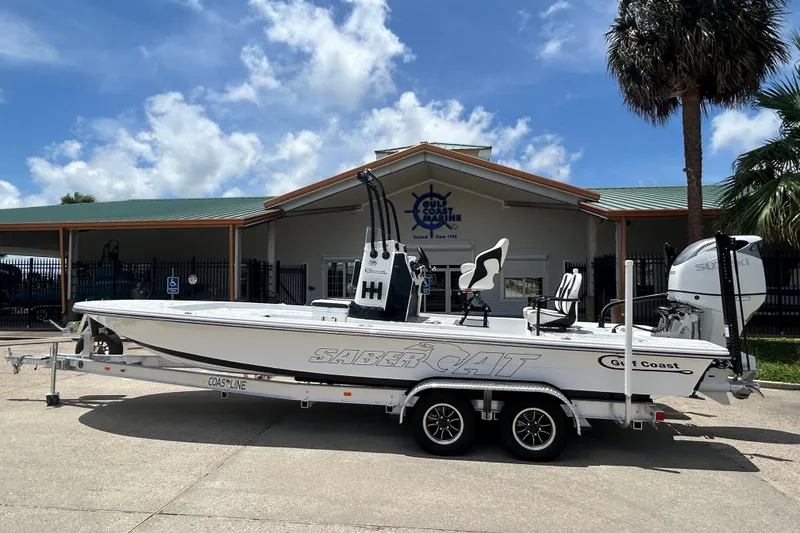 The Image of 2026 Gulf Coast Saber Cat 25 boat on trailer, parked outside a marine dealership. - 0