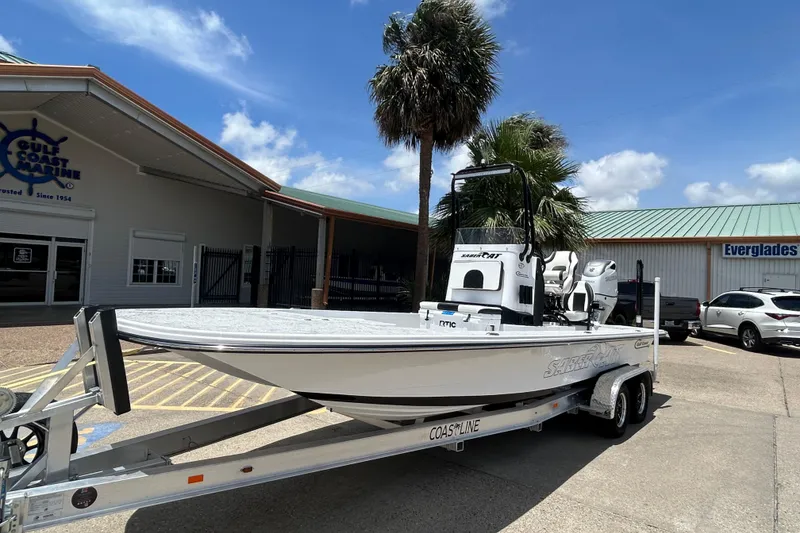 Slide: The Image of 2026 Gulf Coast Saber Cat 25 boat on trailer at dealership under clear sky. - 1