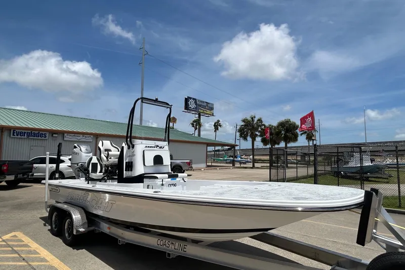 Slide: The Image of 2026 Gulf Coast Saber Cat 25 boat on trailer in sunny marina setting. - 2