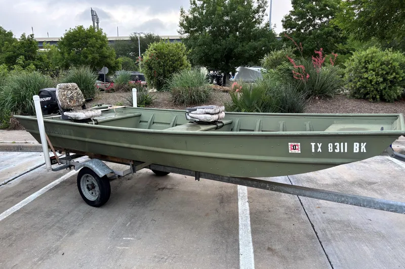 The Image of 2011 Alumacraft 1542 Jon boat on trailer, parked in a lot with greenery background. - 0