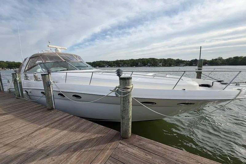 The Image of 2000 Sea Ray Sundancer 460 yacht docked by a wooden pier on a calm lake. - 1