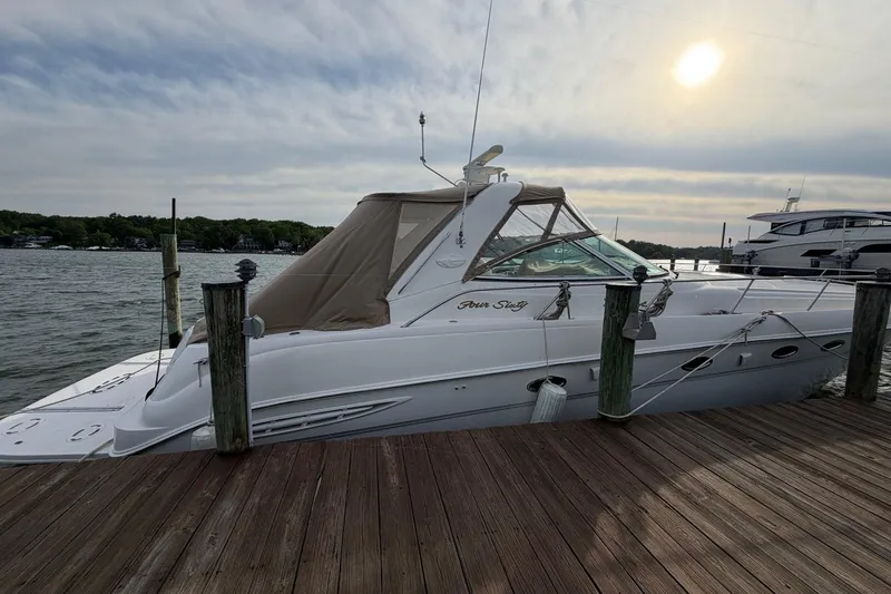 Slide: The Image of 2000 Sea Ray Sundancer 460 yacht docked at a wooden pier under a cloudy sky. - 2