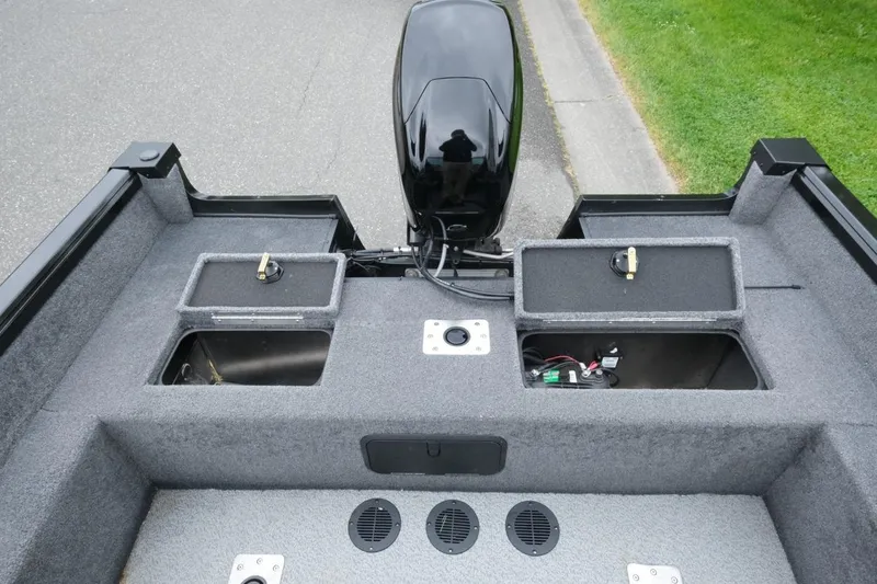Slide: The Image of 2018 Ranger VS1670 WT boat interior with storage compartments and motor, parked on pavement. - 7