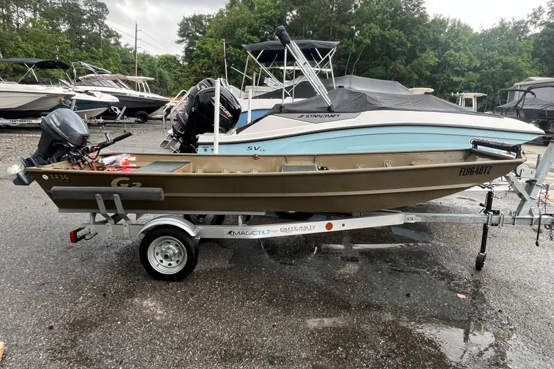 Slide: The Image of 2025 G3 Gator Tough 1436 boat on trailer, parked outdoors with other boats. - 7