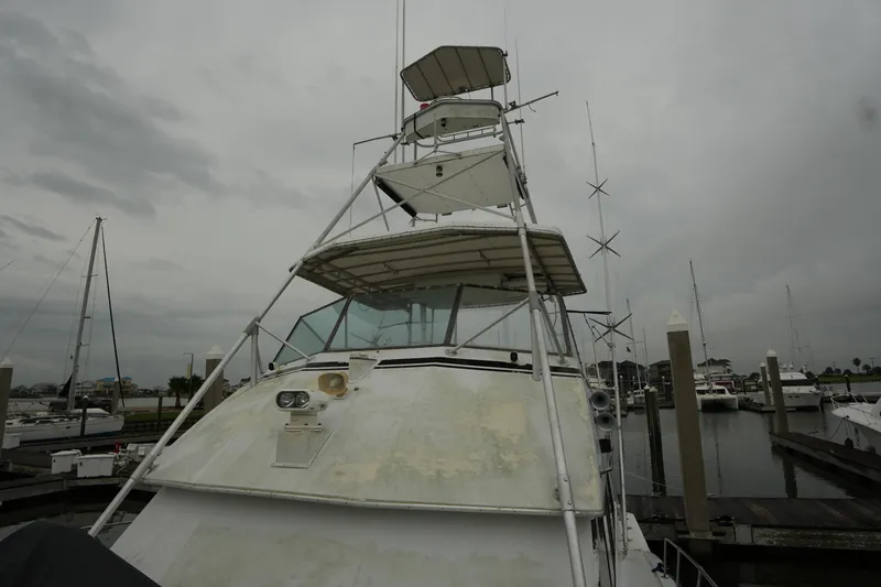Slide: The Image of 1980 Hatteras 50 Convertible yacht docked at marina under cloudy skies. - 11