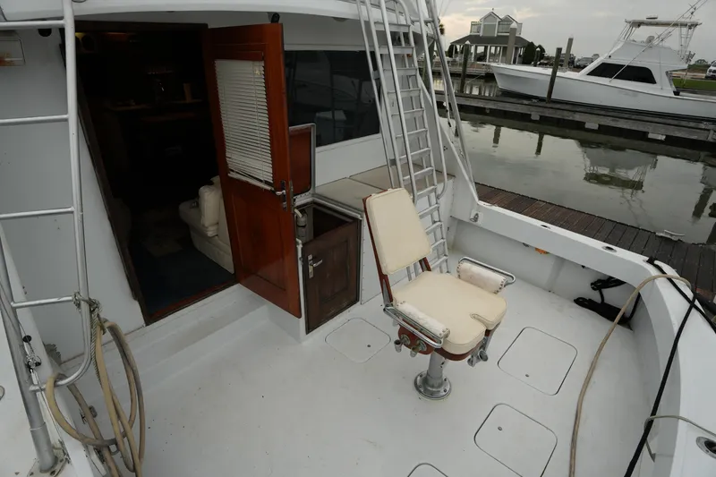 Slide: The Image of 1980 Hatteras 50 Convertible yacht deck with fishing chair and open cabin door. - 12