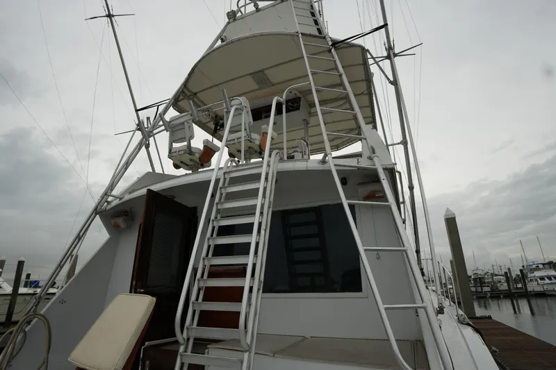 Slide: The Image of 1980 Hatteras 50 Convertible yacht with ladder and upper deck, docked at marina. - 17