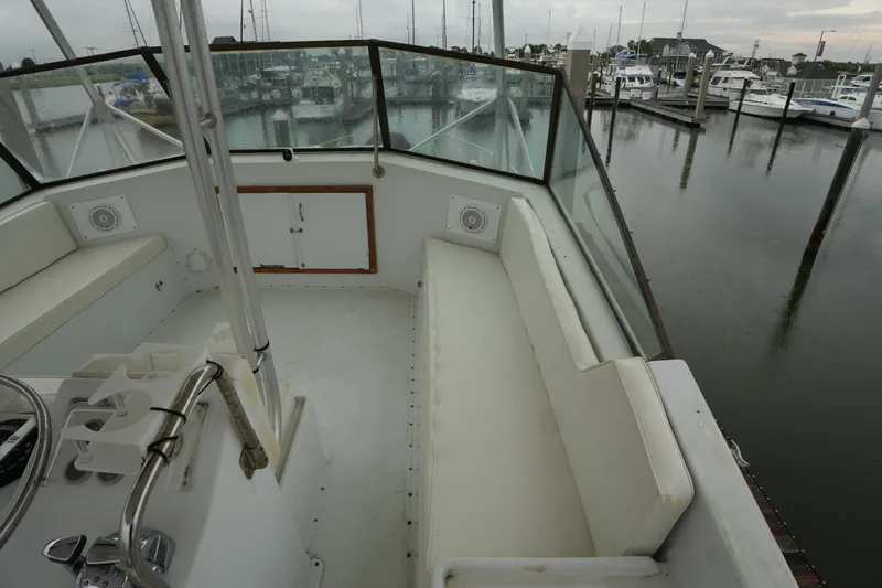 Slide: The Image of 1980 Hatteras 50 Convertible yacht cockpit with white seating, docked in a marina. - 23