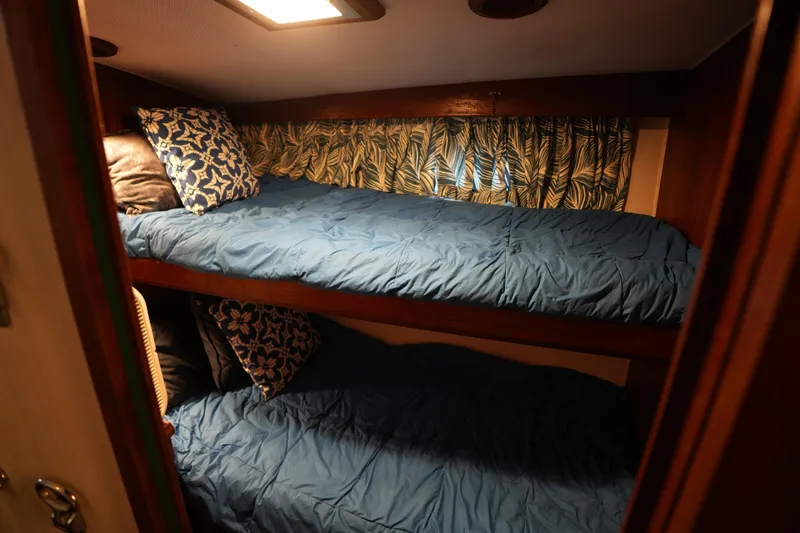 Slide: The Image of Cozy bunk beds in 1980 Hatteras 50 Convertible yacht cabin with blue bedding and patterned pillows. - 48