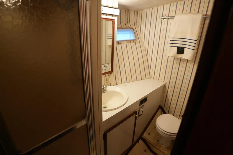 Slide: The Image of Bathroom interior of 1980 Hatteras 50 Convertible yacht with striped wallpaper and compact design. - 51