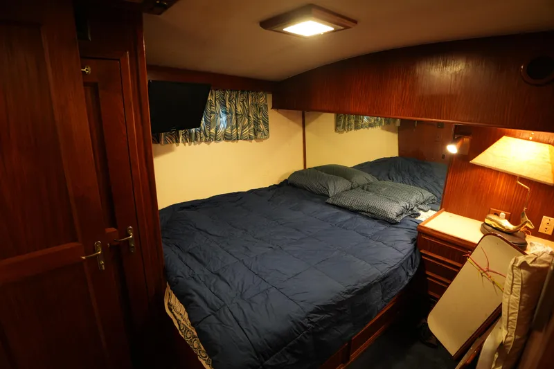 Slide: The Image of Cozy bedroom interior of 1980 Hatteras 50 Convertible yacht with wood paneling and blue bedding. - 54