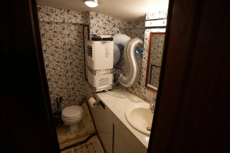 Slide: The Image of 1980 Hatteras 50 Convertible bathroom with floral wallpaper and compact fixtures. - 57