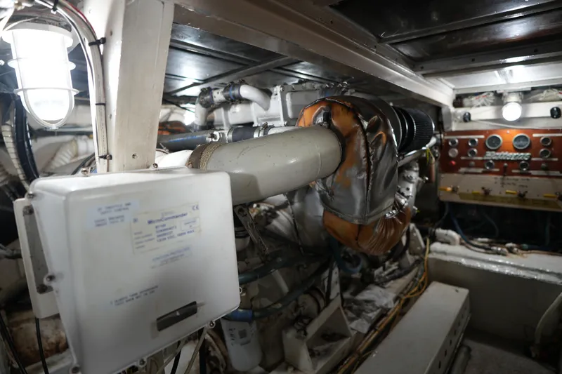 Slide: The Image of Engine room of a 1980 Hatteras 50 Convertible yacht, showcasing machinery and control panels. - 65