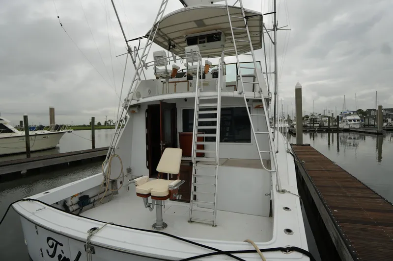 Slide: The Image of 1980 Hatteras 50 Convertible yacht docked at marina, featuring fishing chair and ladder. - 7