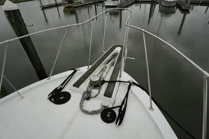 Slide: The Image of Bow of 1980 Hatteras 50 Convertible yacht at marina, featuring anchor and ropes. - 8