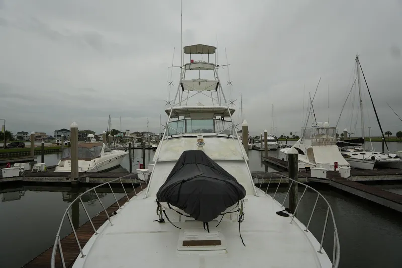Slide: The Image of 1980 Hatteras 50 Convertible yacht docked in a marina under cloudy skies. - 9