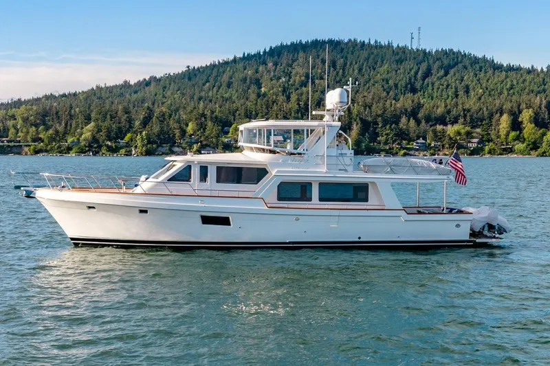 The Image of 2023 Offshore Yachts 64 ELV cruising on a scenic lake with forested hills. - 0