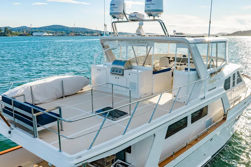 Slide: The Image of 2023 Offshore Yachts 64 ELV luxury yacht on serene water, showcasing spacious deck and modern design. - 44
