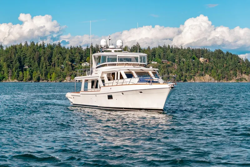 Slide: The Image of 2023 Offshore Yachts 64 ELV cruising on a scenic lake with forested shoreline. - 47