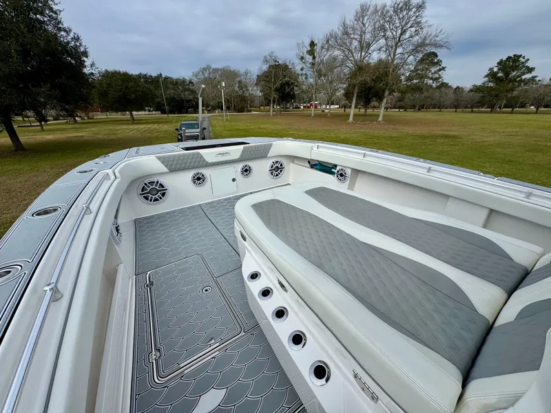 Slide: The Image of 2022 Invincible 35 Catamaran interior with cushioned seating and speakers, parked on grassy area. - 10