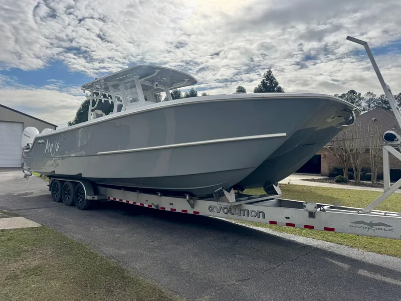 Slide: The Image of 2022 Invincible 35 Catamaran on trailer, parked outdoors under cloudy sky. - 2