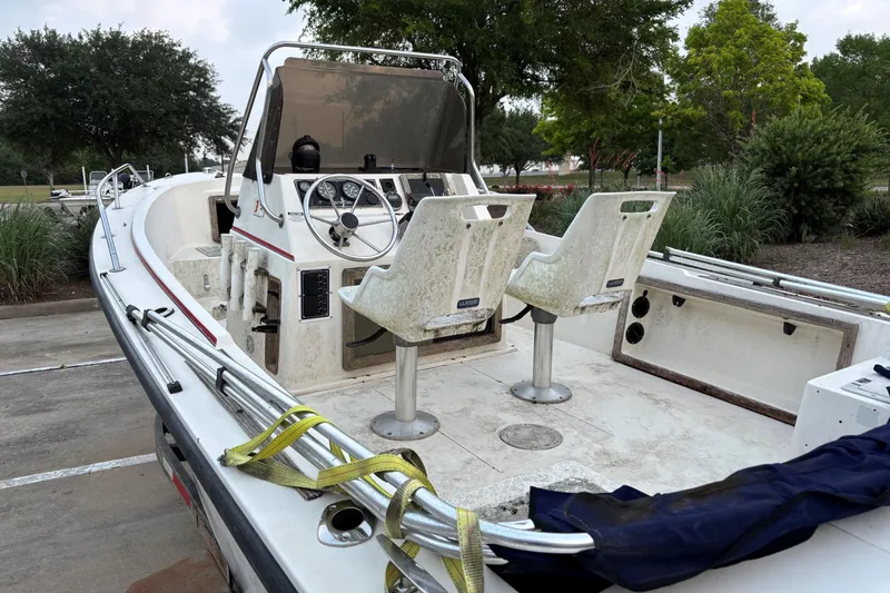 Slide: The Image of 1985 Pro-Line 170 Center Console boat with dual seats and steering wheel, parked outdoors. - 7