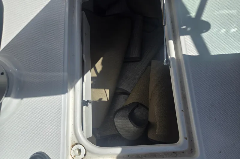 Slide: The Image of Storage compartment with rolled mats on a 2018 Chaparral 267 SSX boat. - 13