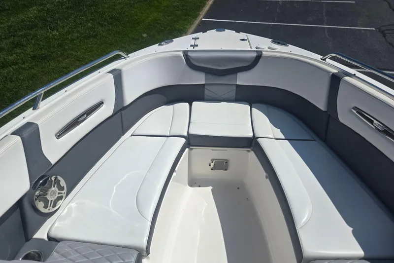 Slide: The Image of 2018 Chaparral 267 SSX boat interior with white and gray seating, parked on grass. - 17
