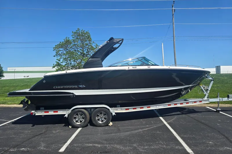 Slide: The Image of 2018 Chaparral 267 SSX boat on trailer, parked outdoors under clear blue sky. - 4