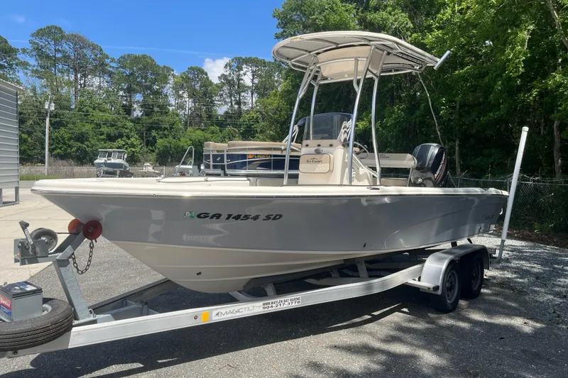 Slide: The Image of 2021 Sea Chaser 21 LX boat on trailer, parked outdoors with trees in background. - 2