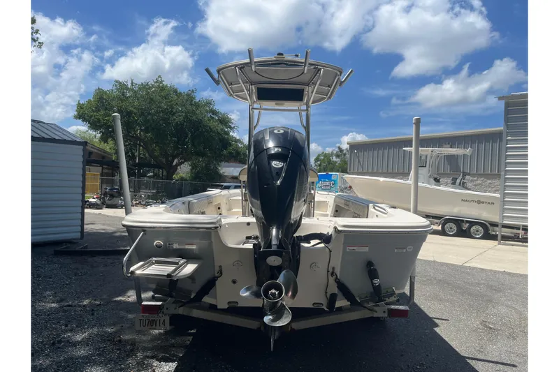 Slide: The Image of 2021 Sea Chaser 21 LX boat with outboard motor, parked outdoors under a blue sky. - 4