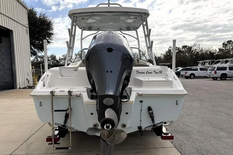 Slide: The Image of 2024 Key West 239 DFS boat with outboard motor, parked outdoors near a warehouse. - 11
