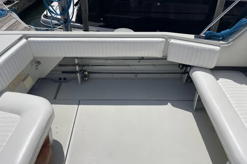 Slide: The Image of 1997 Stamas 310 Express boat interior with white cushioned seating and fishing rod storage. - 10