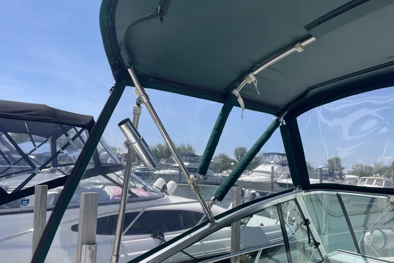 Slide: The Image of 1997 Stamas 310 Express boat with green canopy, docked at marina under clear blue sky. - 14