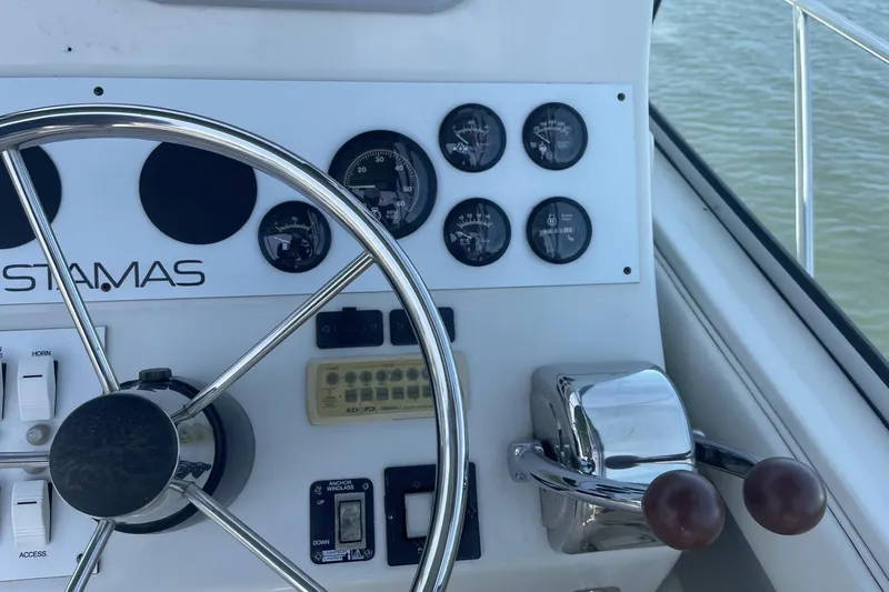 Slide: The Image of 1997 Stamas 310 Express boat dashboard with steering wheel and control gauges. - 17