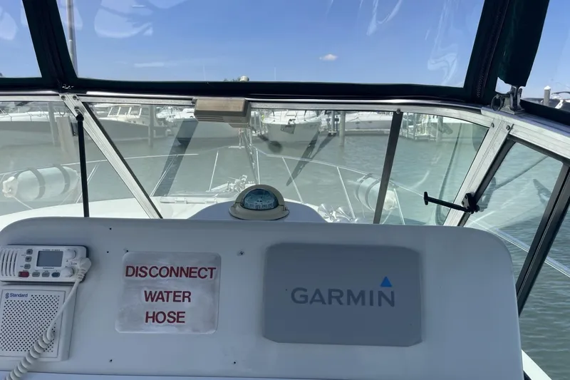 Slide: The Image of 1997 Stamas 310 Express boat cockpit with Garmin navigation and water hose warning sign. - 18