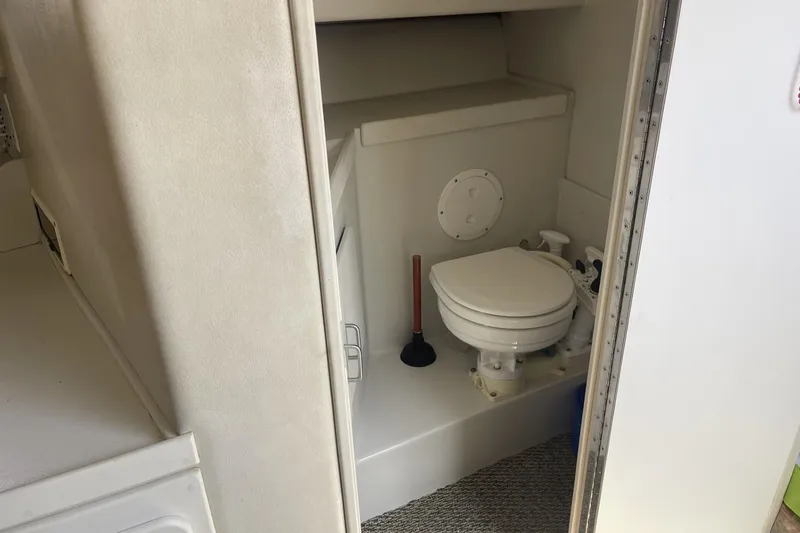 Slide: The Image of 1997 Stamas 310 Express boat bathroom interior with toilet and plunger. - 33